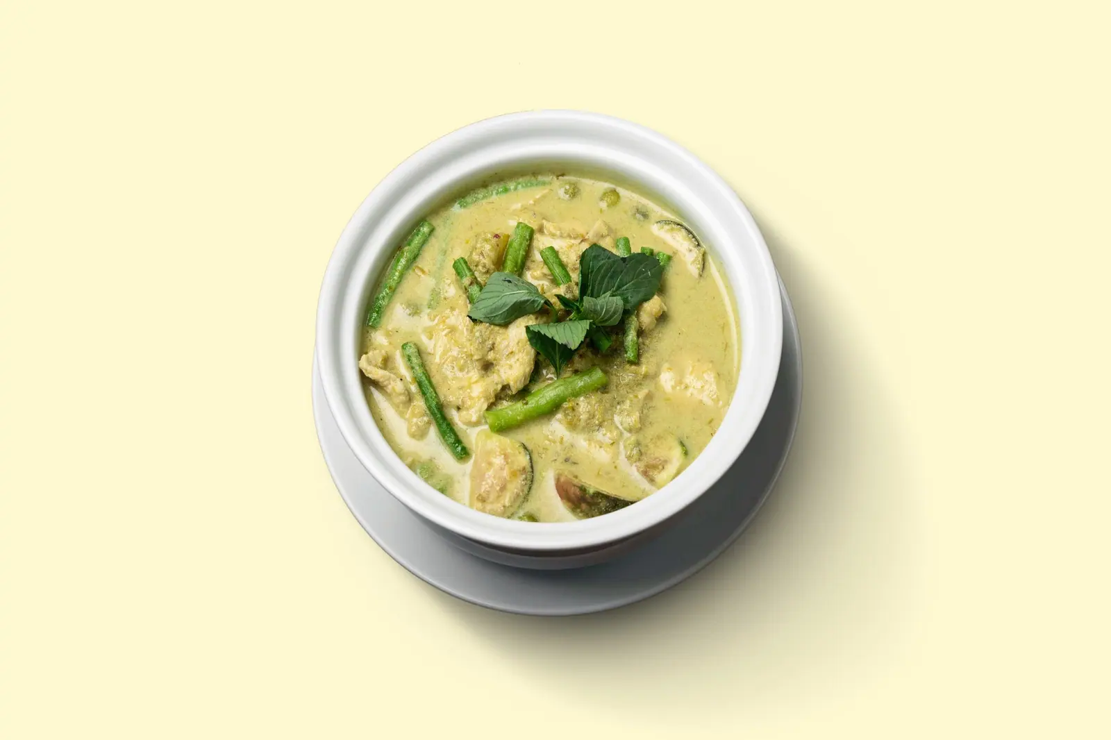 Grünes Curry mit Rindfleisch in einer Schale, cremefarbener Grund