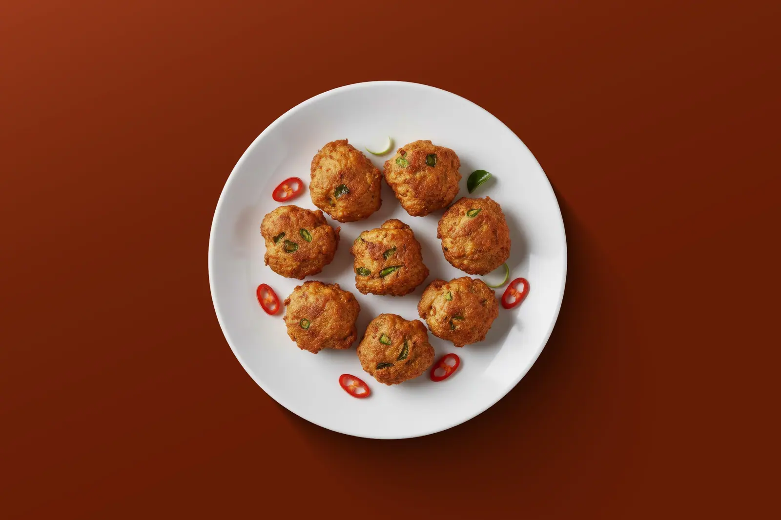 Spicy chicken bites on a white plate, red background