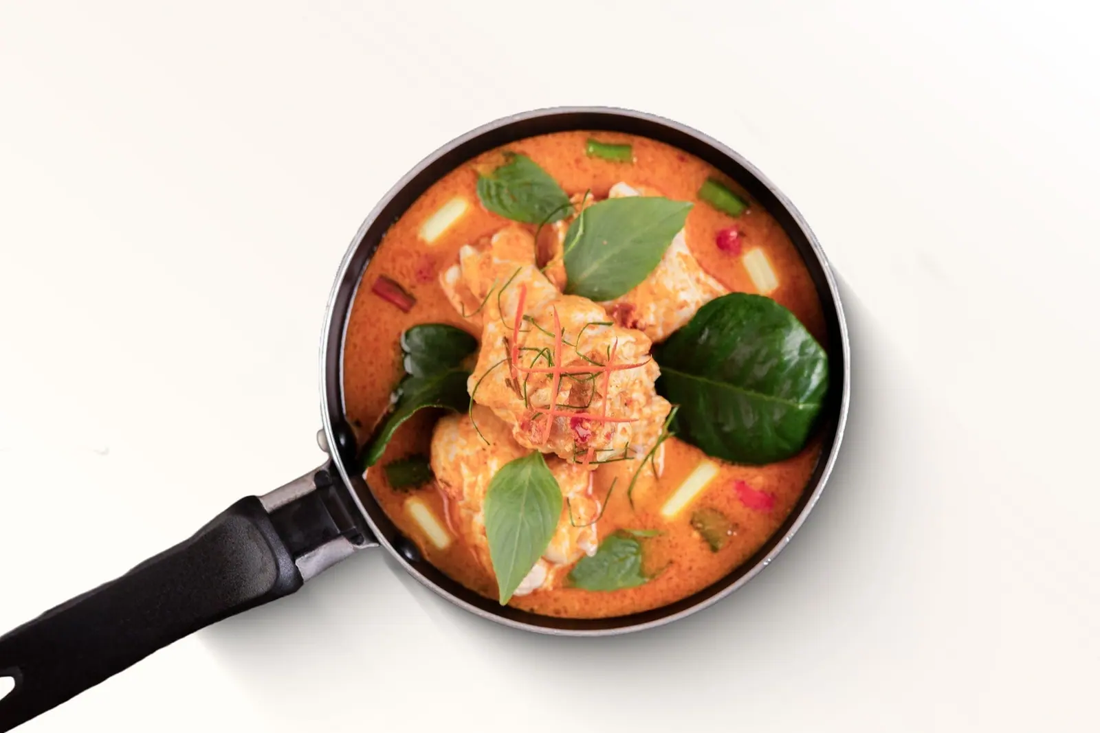 Red curry with salmon in a pan
